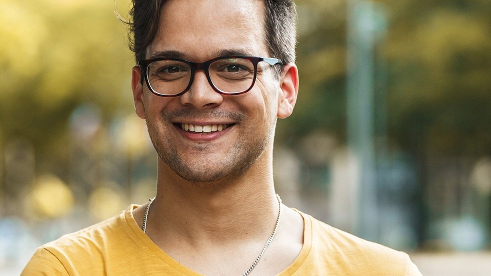 kolorowe zdjęcie przedstawiające młodego mężczyznę trzymającego książki