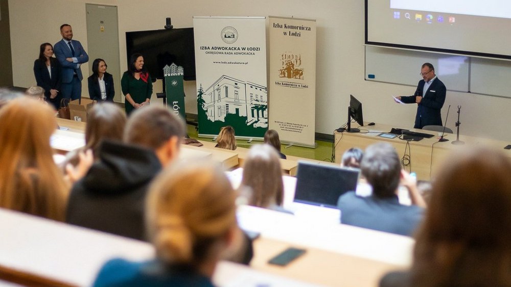 Grupa osób na auli uniwersyteckiej.