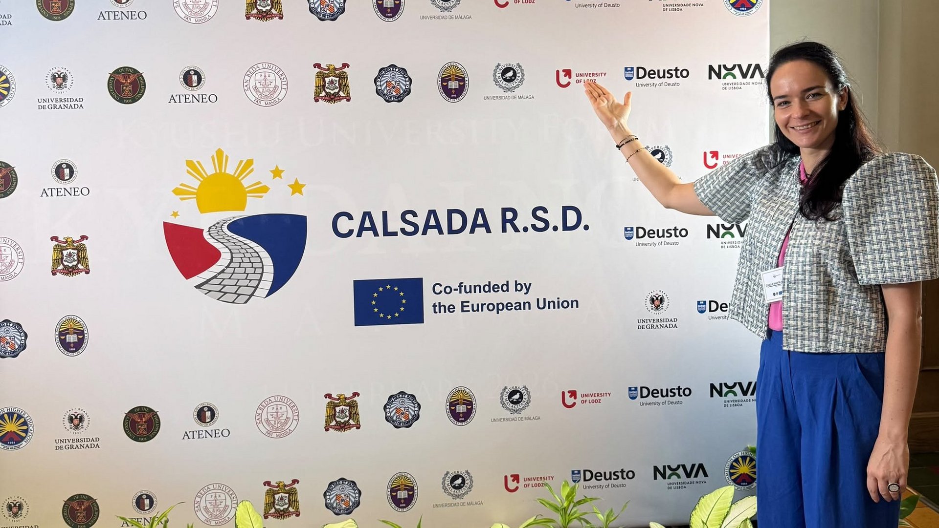 a woman standing in front of a backdrop displaying institutional logos
