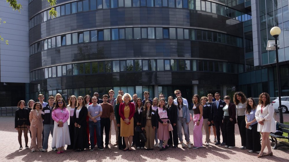 students and lecturers posing for a photo in front of the faculty building