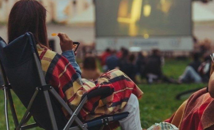 a decorative element: a woman sitting on a deckchair and watching a film at an outdoor cinema