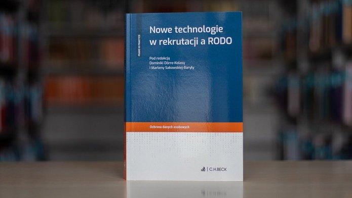 Książka na tle zbiorów bibliotecznych