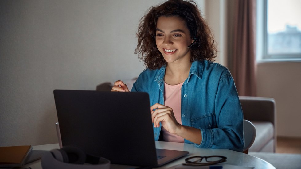 Happy young woman freelancer working online on computer laptop. A student is smiling in front of her laptop.