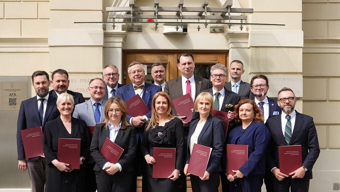 Grupa ludzi trzymająca podpisane porozumienia